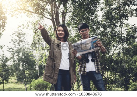 Two Young Traveler with backpack, are holding map relaxing in greens jungle and enjoying with outdoor forest on background Summer vacations and Lifestyle hiking concept.