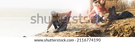 Two young volunteers cleaning up the beach from various trash