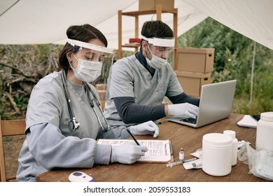 Two Young Volunteers Filling In Medical Documents And Entering Data In Database While Working In Refugee Camp