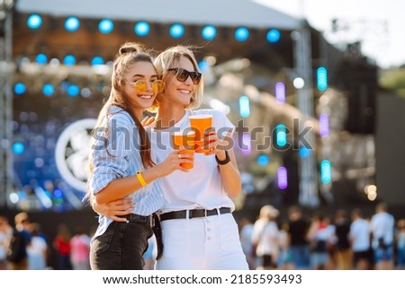 Two young woman with beer at beach party. Summer holiday, vacation concept. Friendship and celebration concept.