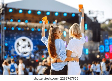 Two young woman  with beer at music festival. Beach party, summer holiday.