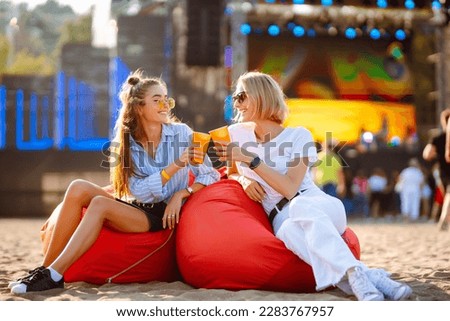 Two young woman  with beer at music festival. Beach party, summer holiday.