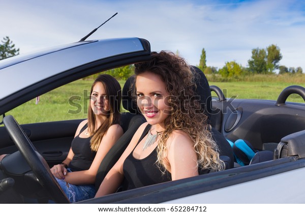 two young woman in\
cabriolet car in summer