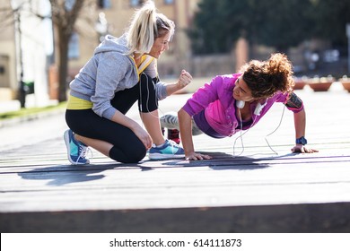 Two Young Woman Doing Pushups And Other Workout On The Street,early In The Morning.