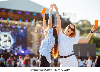 Two young woman drinking beer and having fun at Beach party together. Happy girlfriends  having fun at music festival. Summer holiday, vacation concept. - Shutterstock ID 2174732219