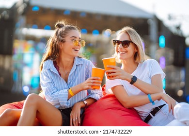 Two Young Woman Drinking Beer And Having Fun At Beach Party Together. Happy Girlfriends  Having Fun At Music Festival. Summer Holiday, Vacation Concept.