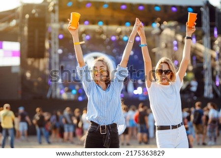 Two young woman drinking beer and having fun at Beach party together. Happy girlfriends  having fun at music festival. Summer holiday, vacation concept.