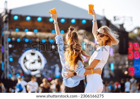 Two young woman drinking beer and having fun at Beach party together. Music festival. Summer holiday, vacation concept.