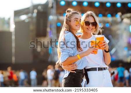 Two young woman  having a great time at a music festival. Happy girlfriends rinking beer and having fun at Beach party. Summer holiday, vacation concept.