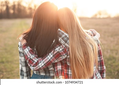 Two young woman looking on the sunset and hugging. Best friends