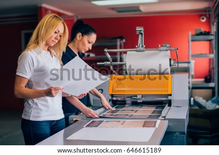 Two young woman working in printing factory. Printing Press