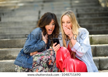 Similar – Two women laughing looking at their smart phone