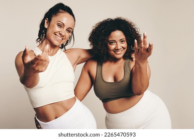 Two young women in athletic wear dance and work out together, embodying a healthy and active lifestyle. Energetic female athletes expressing their shared passion for fitness in a studio. - Powered by Shutterstock