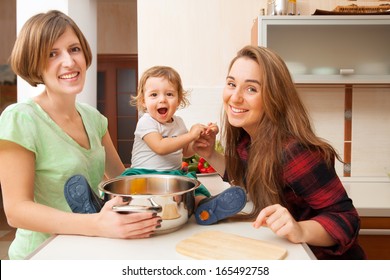 two young women with a baby in the kitchen
