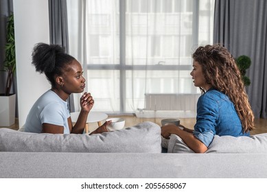 Two Young Women Best Friends Sitting On The Sofa At Home Drinking Tea Or Coffee Complaining On Her Boyfriend Or Husband To How He Changed And Become Jealous