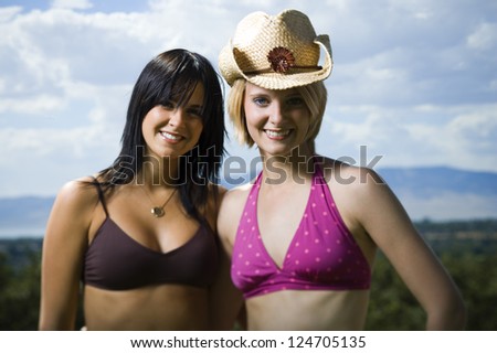 Two young women in bikini posing against landscape