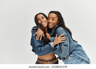 Two young women celebrate friendship while wearing fashionable denim attire with playful energy. - Powered by Shutterstock