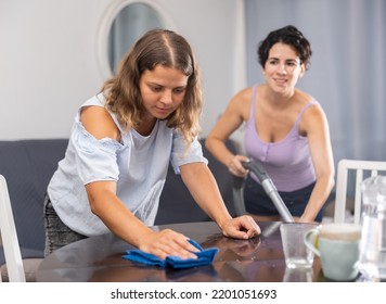 Two Young Women Cleaning Living Room At Home. Concept Of Homosexual Family Relationships