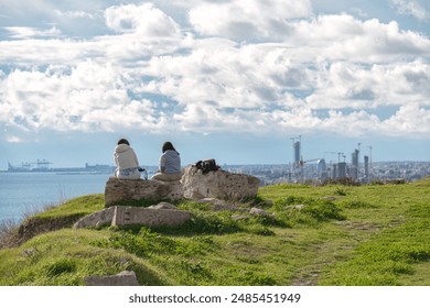 Two young women contemplating cityscape view from Amathus ruins on green hill. Limassol, Cyprus - Powered by Shutterstock