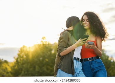 two young women couple hugging on a terrace while using mobile - Powered by Shutterstock