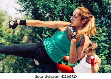 Two young women demonstrating side kicks in TaeBo training - Powered by Shutterstock