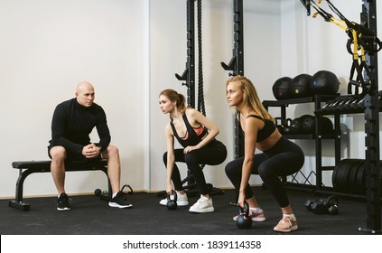 Two Young Women Doing Kettlebell Lifting. Crossfit Workout With A Personal Trainer Or Coach. Private Training Concept In A Small Private Sports Studio