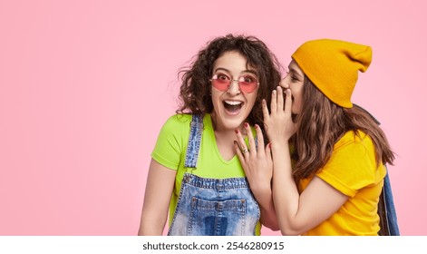 Two young women dressed in vibrant clothes, sharing secrets and laughing together. Friendship and fun concept against a bright pink background. - Powered by Shutterstock