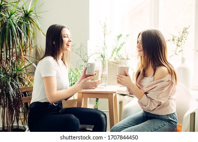 Two Young Women Are Drinking Coffee At Home.