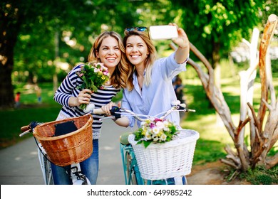 Two young women exploring the city on bicycles and doing selfie