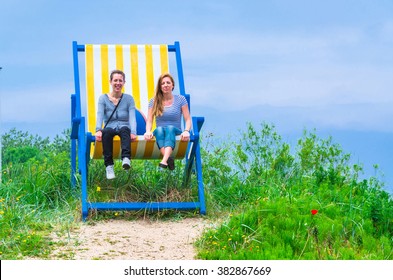 Two Young Women In A Giant Deckchair.