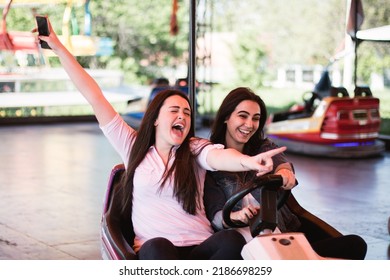 Two Young Women Having A Fun Bumper Car Ride At The Amusement Park During Summer.