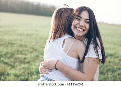 Two Young Women Hugging Outdoors. Asian Girl Looking At The Camera And Smiling. Best Friends