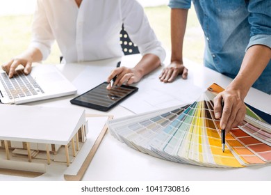 Two Young Women Interior Design Or Graphic Designer Working On Project Of Architecture Drawing With Work Tools And Color Swatches, Colour Chart In Digital Tablet At Workplace.