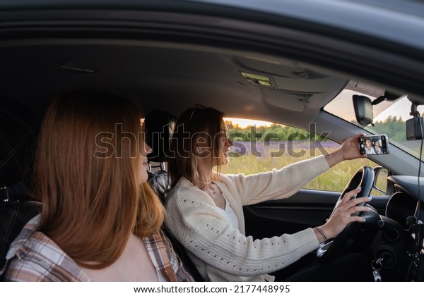 Two young\
women laughing in the car during a summer road trip. Best friends\
have fun together as they drive through the countryside. A happy\
couple of girls relaxing on a road\
trip.