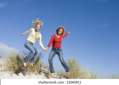 Two young women leaping in air at beach