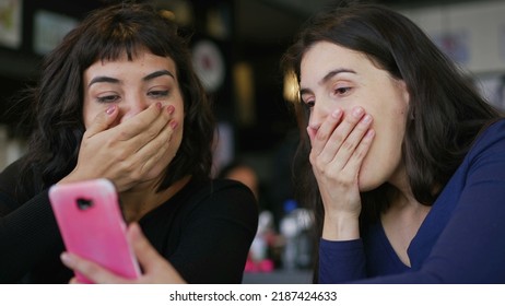 Two Young Women Looking At Smartphone Device Screen Smiling. Female Friends Sharing Information Watching Content Online