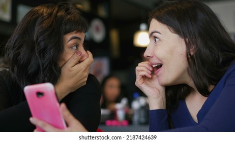 Two Young Women Looking At Smartphone Device Screen Smiling. Female Friends Sharing Information Watching Content Online