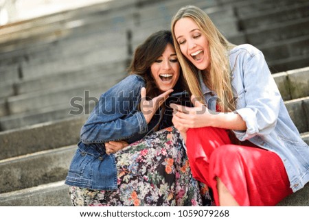 Similar – Two women laughing looking at their smart phone