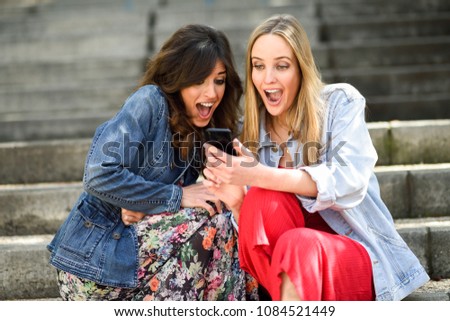 Two women laughing looking at their smart phone