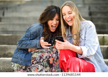 Similar – Two women laughing looking at their smart phone