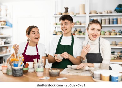 Two young women and young man making clay pottery in workshop - Powered by Shutterstock