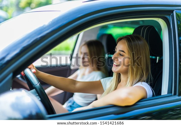 Two young women on car trip.They are\
driving the car and having fun. Positive\
emotions.