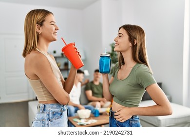 Two Young Women On Party Smiling Happy And Drinking Soda At Home.