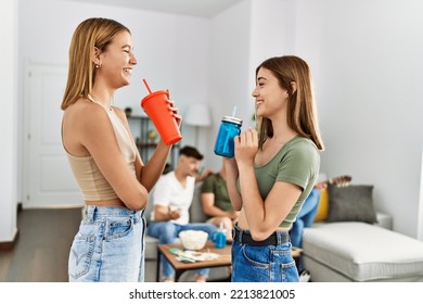 Two Young Women On Party Smiling Happy And Drinking Soda At Home.