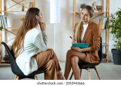 Two young women, patient and doctor discussing psychological problems at the appointment with psychologist. Mental health, psychotherapy, support concept. Look with attention, interest - Shutterstock ID 2053943666