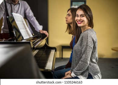 Two young women at a piano time with a teacher