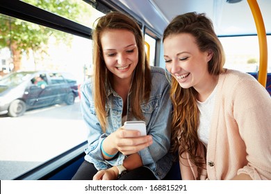 Two Young Women Reading Text Message On Bus - Powered by Shutterstock