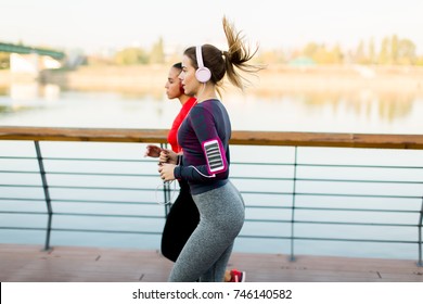 Two young women running by the river in the morning - Shutterstock ID 746140582