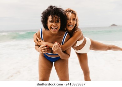Two young women share a moment of friendship and happiness on the beach. With wide smiles and carefree laughter, they embrace each other, fully immersed in the fun and leisure of the coastal paradise. - Powered by Shutterstock