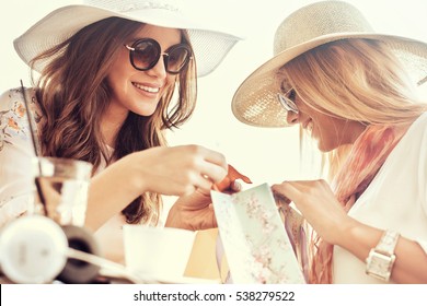 Two young women sharing their new purchases with each other.They having coffee break after good shopping.